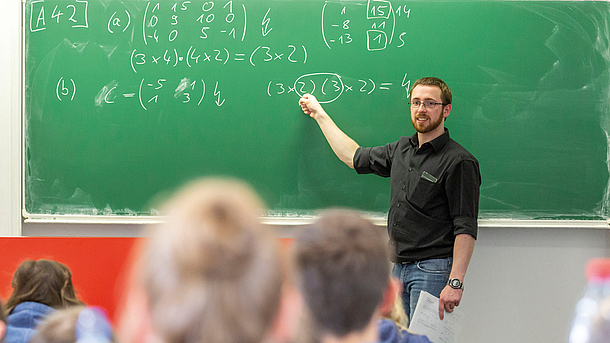 Tutor erklärt angehenden Studierenden Mathematik an der Tafel
