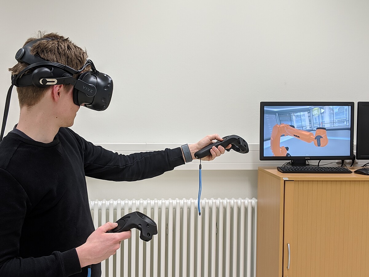 Junger Mann trägt eine VR Brille und steuert einen Roboter
