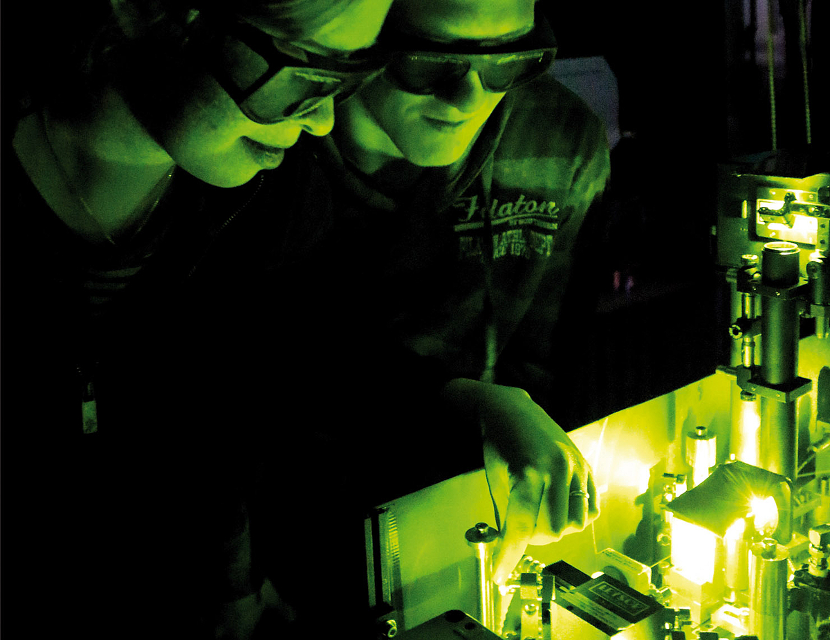 Foto: Zwei Studieninteressierte sehen sich einen Laser an